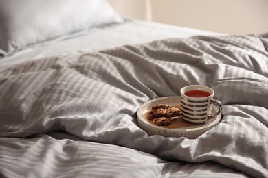 Tray with cup of tea and cookies on soft blanket. Space for text