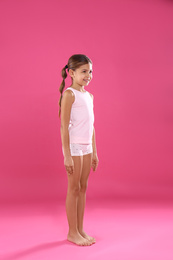 Cute little girl in underwear on pink background