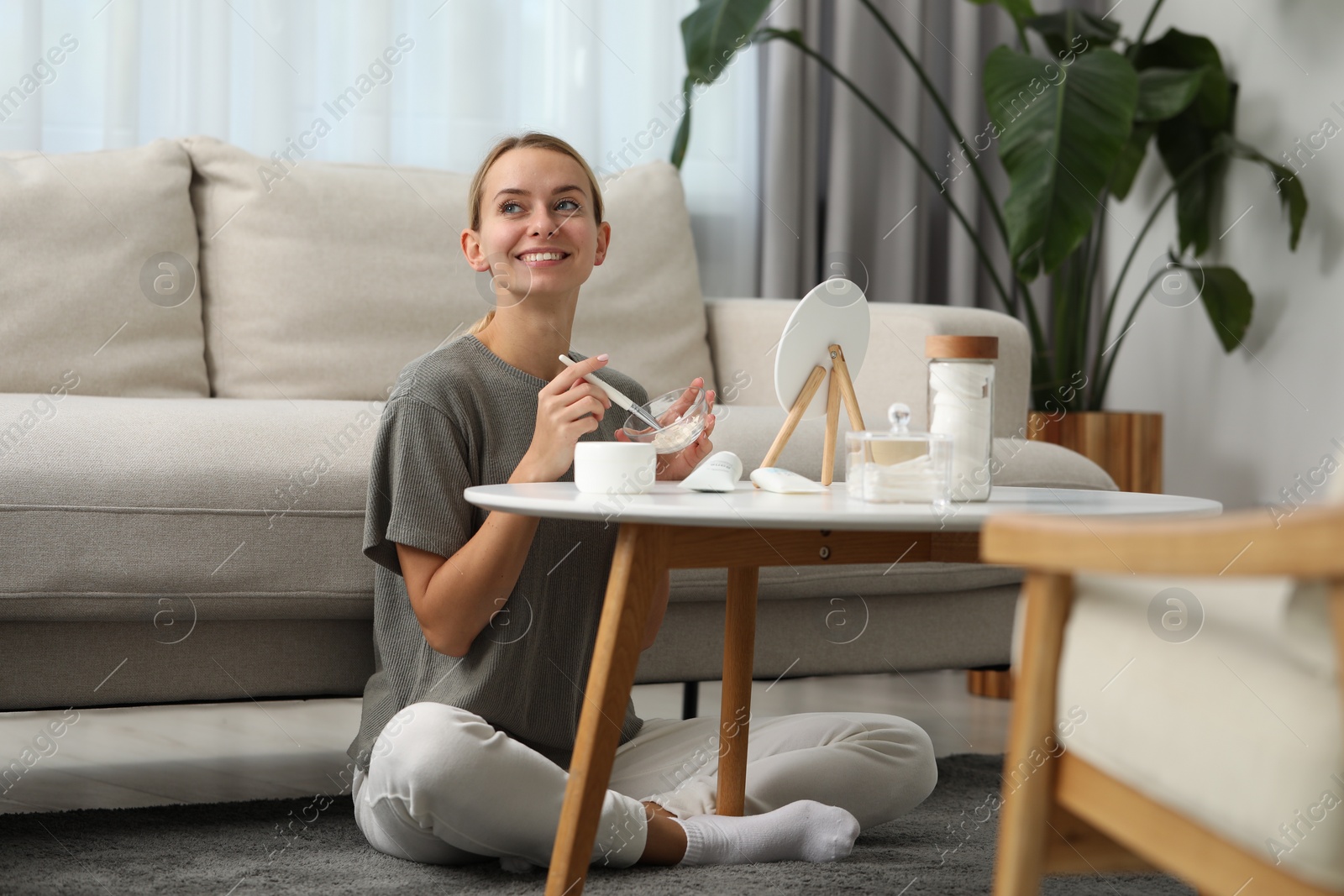 Photo of Young woman preparing face mask in front of mirror at home. Spa treatments