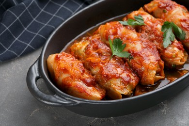 Photo of Delicious stuffed cabbage rolls cooked with tomato sauce on grey table, closeup