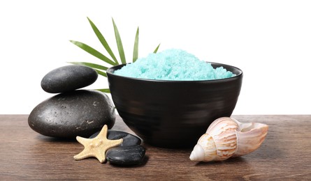 Light blue sea salt in bowl, spa stones, starfish, seashell and palm leaf on wooden table against white background