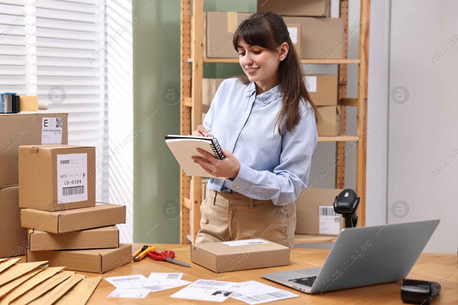 Photo of Parcel packing. Post office worker writing notes indoors