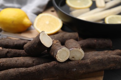Photo of Raw salsify roots with lemon on table, closeup