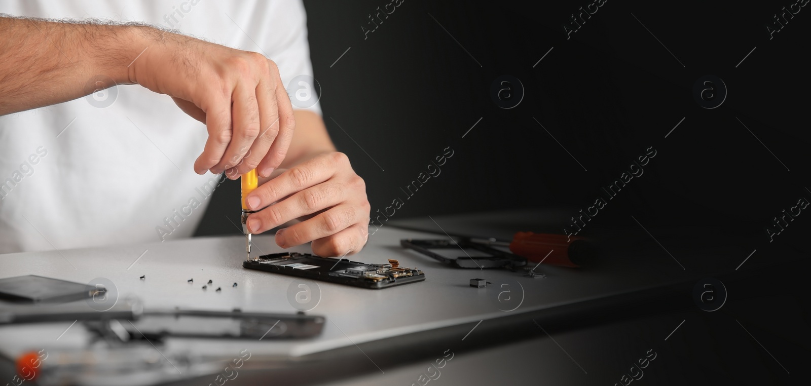 Image of Technician repairing mobile phone at table, space for text. Banner design