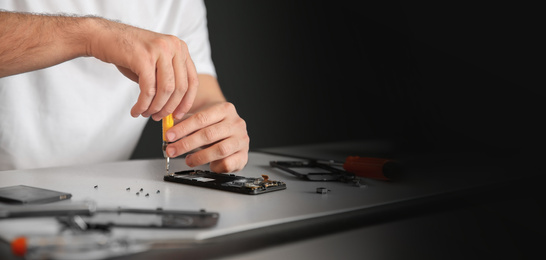 Image of Technician repairing mobile phone at table, space for text. Banner design