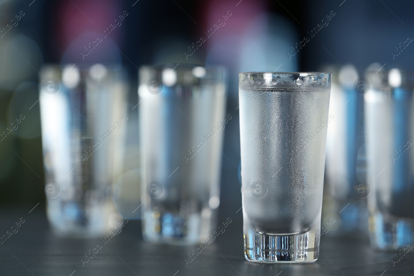 Photo of Shot of vodka on table against blurred background. Space for text