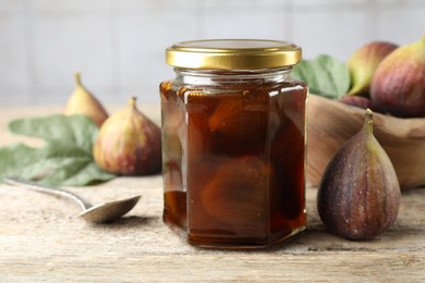 Jar of tasty sweet jam and fresh figs on wooden table