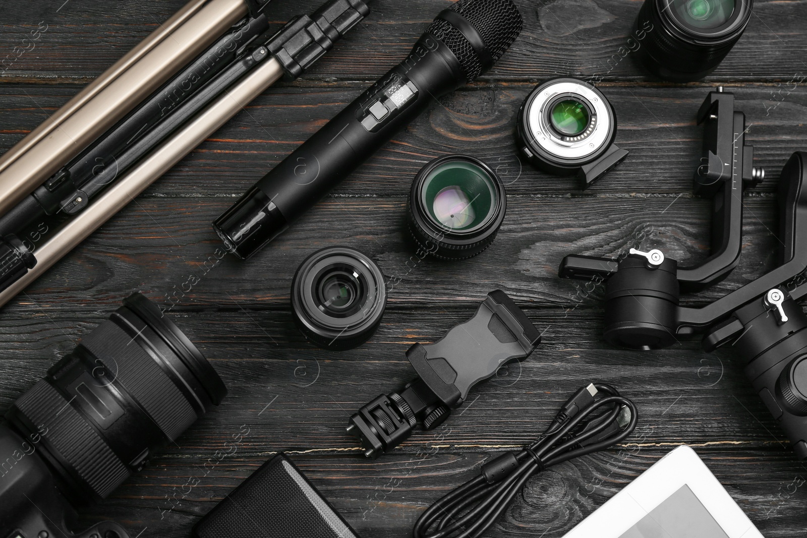 Photo of Flat lay composition with camera and video production equipment on black wooden table