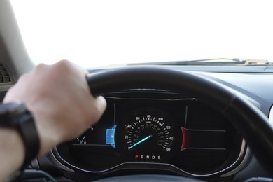 Man driving car with speedometer on dashboard, closeup