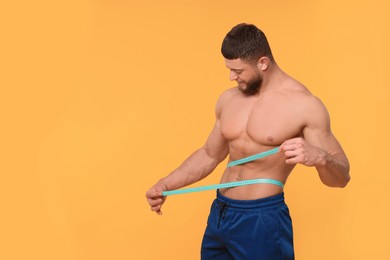 Photo of Athletic man measuring waist with tape on orange background, space for text. Weight loss concept
