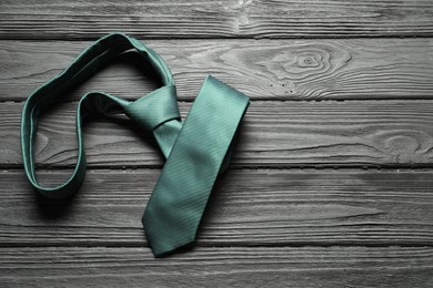 Photo of One green necktie on black wooden table, top view. Space for text