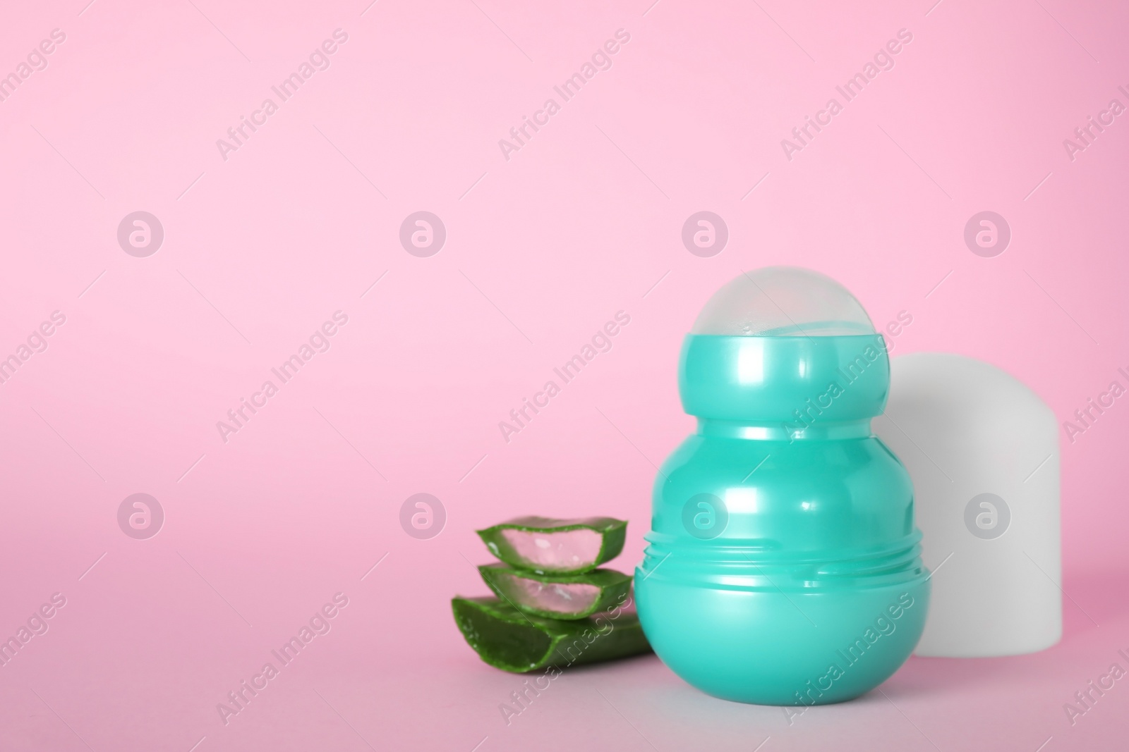 Photo of Natural roll-on deodorant and aloe on pink background, space for text