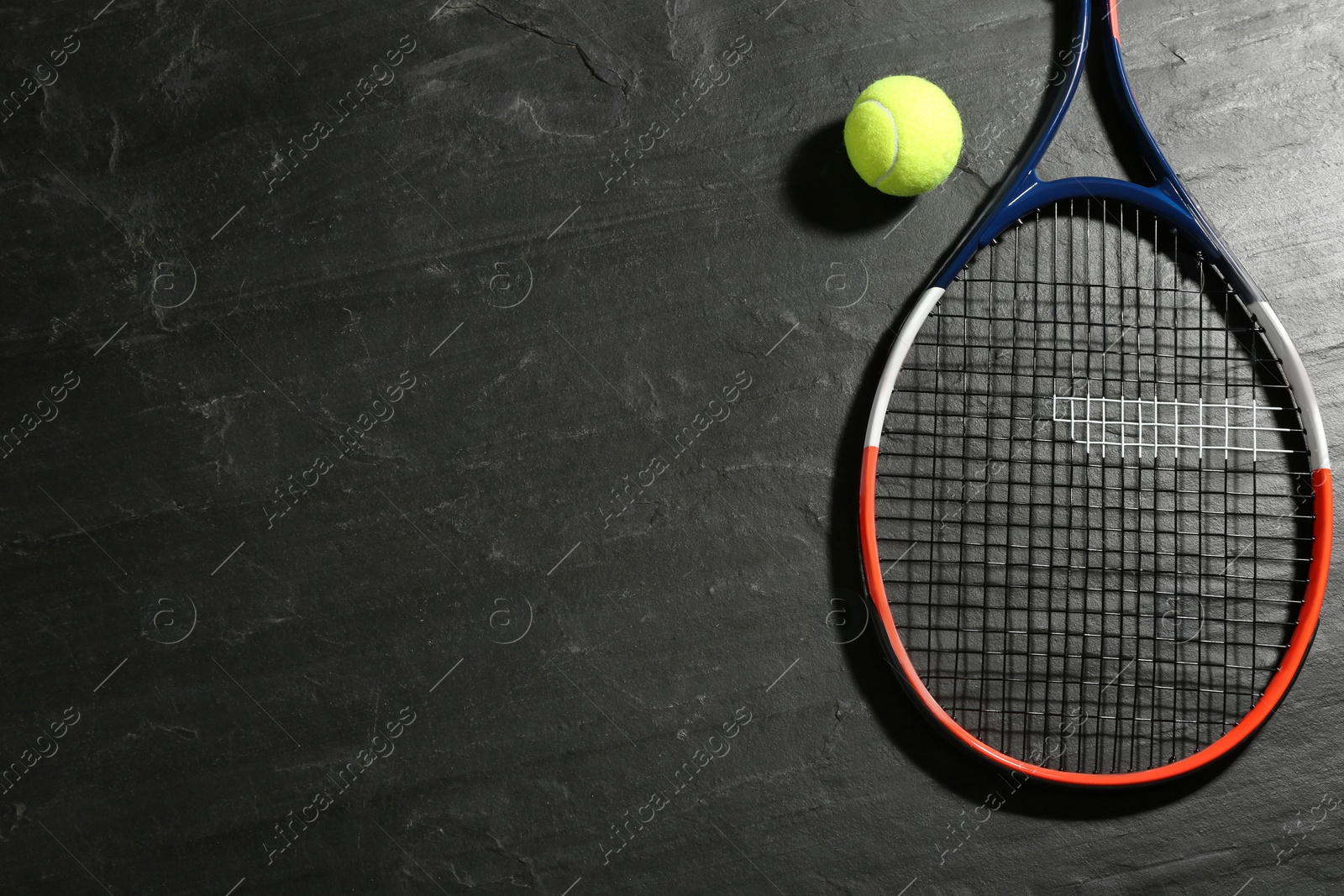 Photo of Tennis racket and ball on black table, flat lay. Space for text