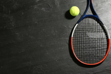 Tennis racket and ball on black table, flat lay. Space for text