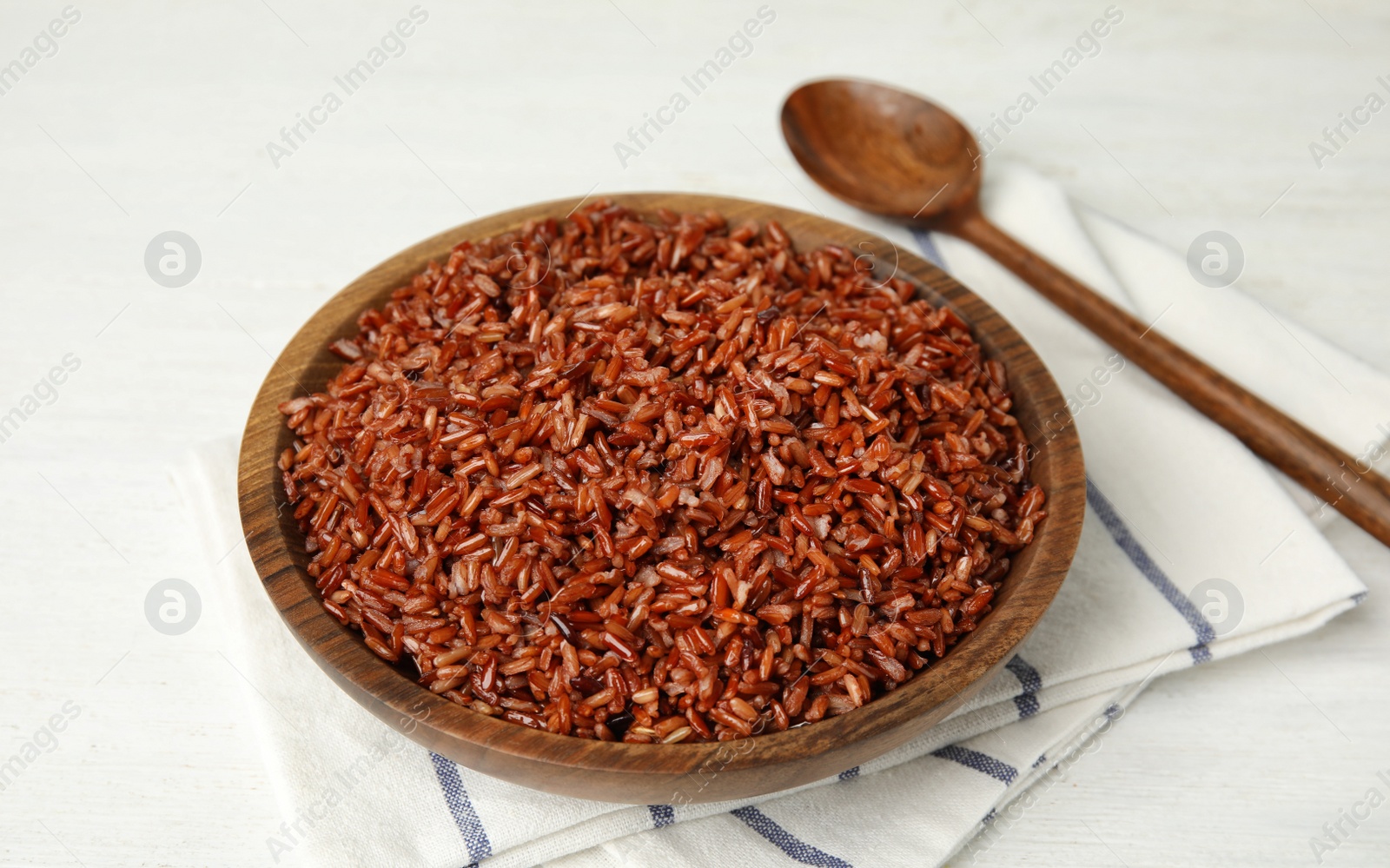 Photo of Wooden bowl with delicious cooked brown rice on white table