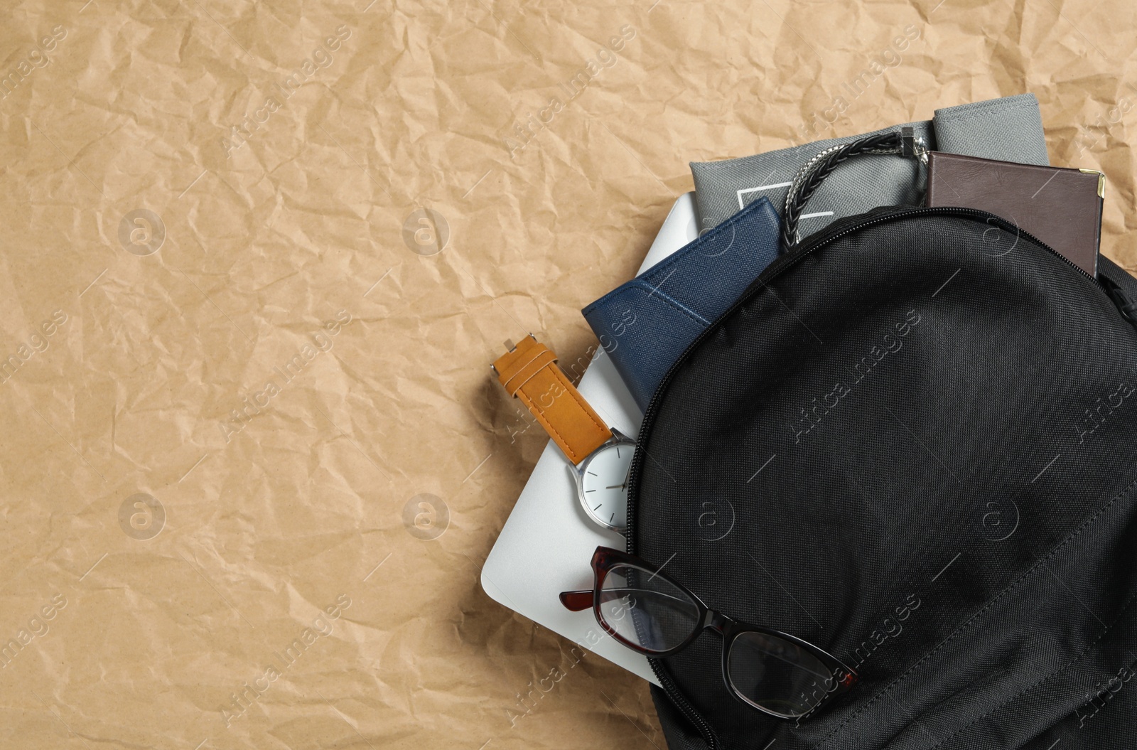 Photo of Stylish urban backpack with different items on parchment paper, top view. Space for text