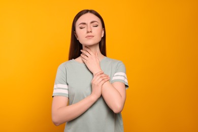 Photo of Young woman with sore throat on orange background
