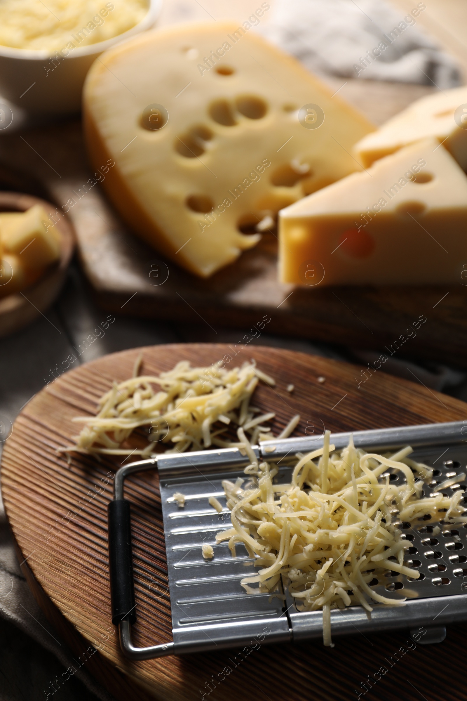 Photo of Grated, cut cheese and grater on table, closeup