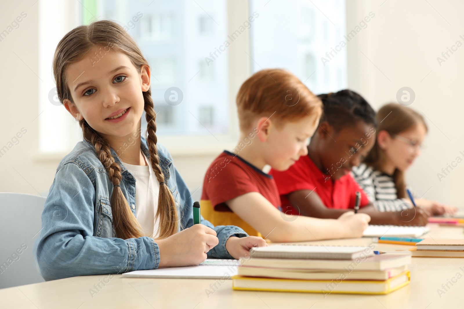 Photo of Smiling girl with her classmates studying in classroom at school