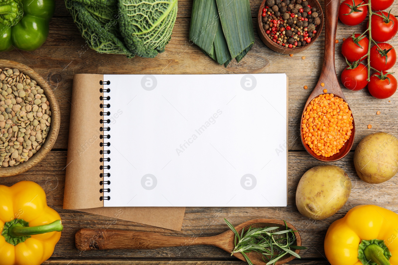 Photo of Recipe book surrounded by different ingredients on wooden table, flat lay with space for text. Cooking classes