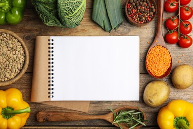 Recipe book surrounded by different ingredients on wooden table, flat lay with space for text. Cooking classes