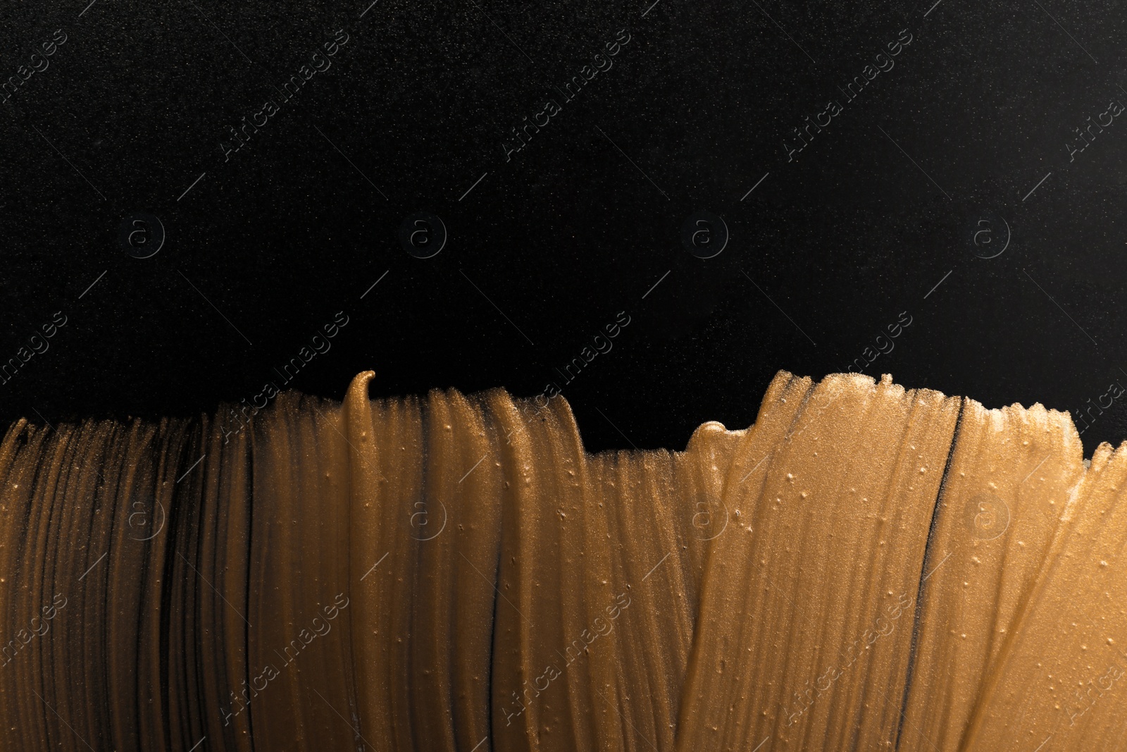 Photo of Golden paint brush strokes on black background. Space for text