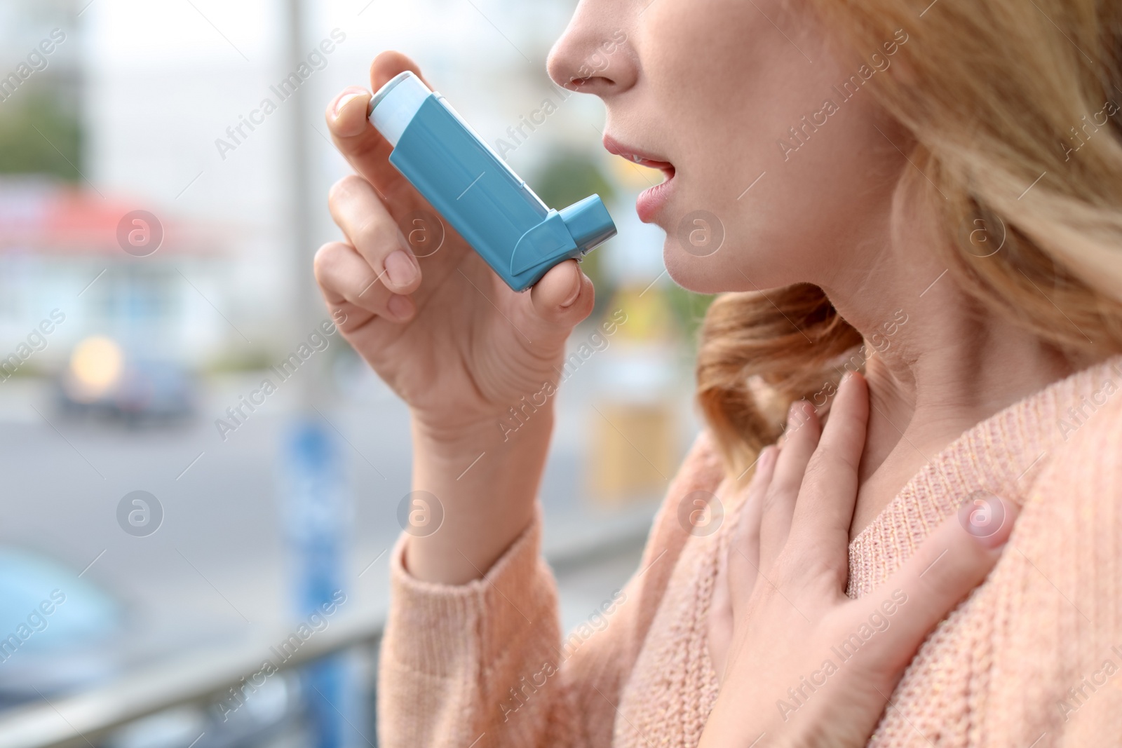 Photo of Woman using asthma inhaler outdoors, closeup. Health care