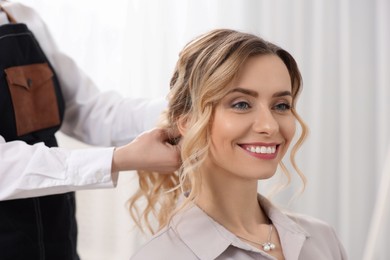 Hair styling. Professional hairdresser working with smiling client indoors, closeup