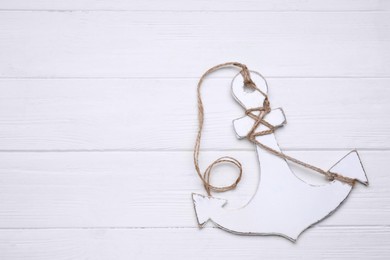 Photo of Anchor with hemp rope on white wooden table, top view. Space for text