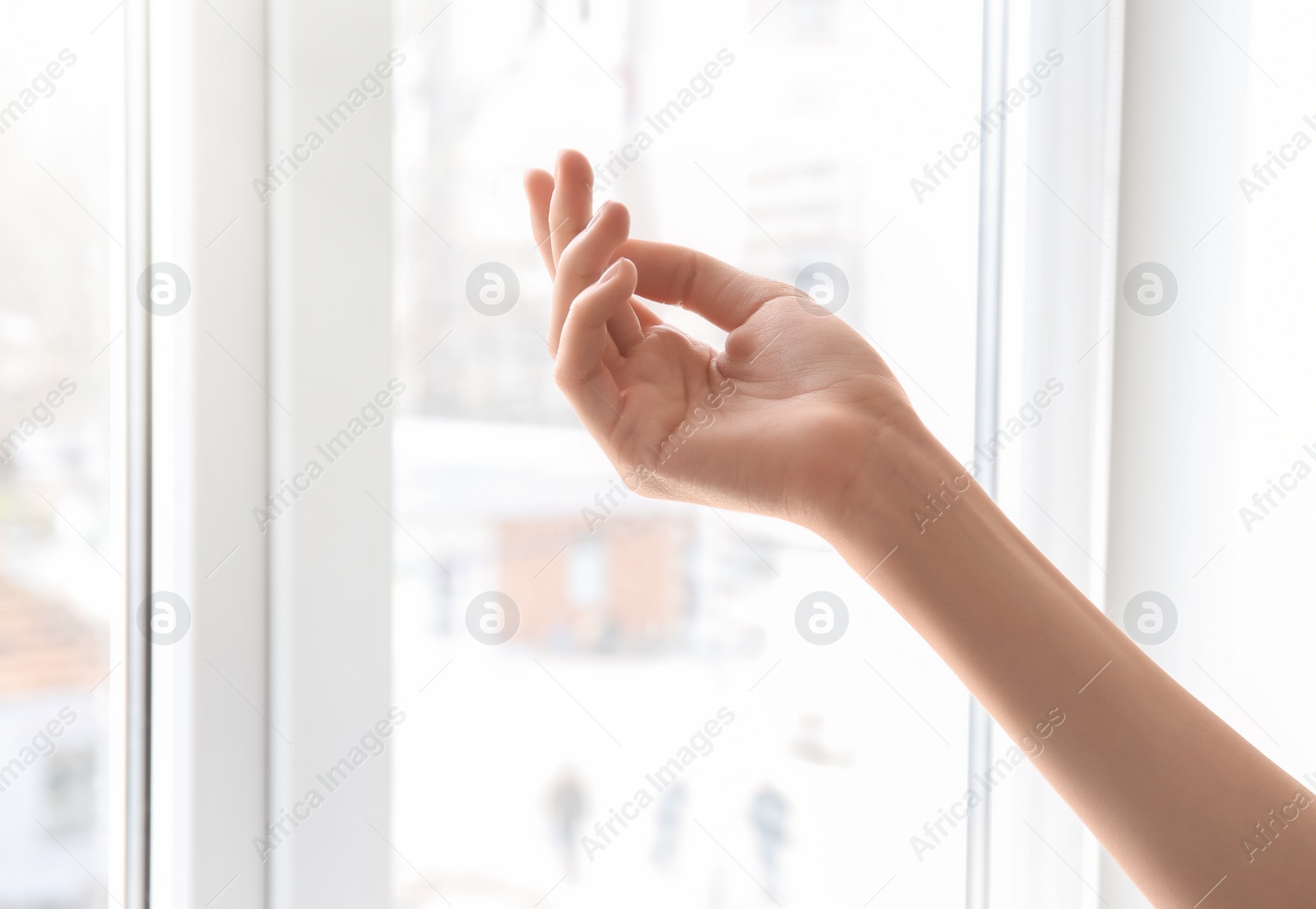 Photo of Young woman against window. Focus on hand moisturized with cream