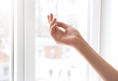 Photo of Young woman against window. Focus on hand moisturized with cream