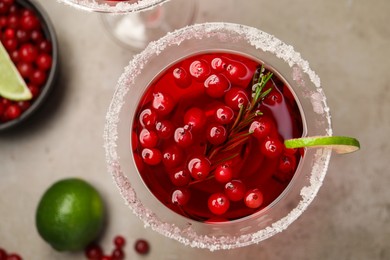 Tasty cranberry cocktail with rosemary and lime in glass on grey table, flat lay