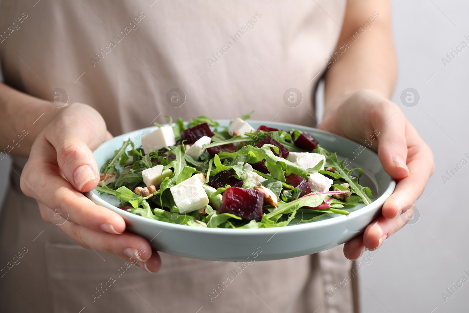 Photo of Woman with fresh delicious beet salad on light background, closeup