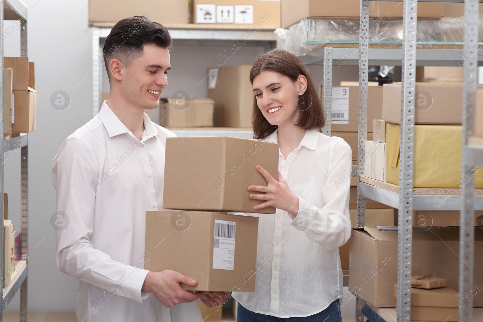 Photo of Post office workers with parcels near rack indoors