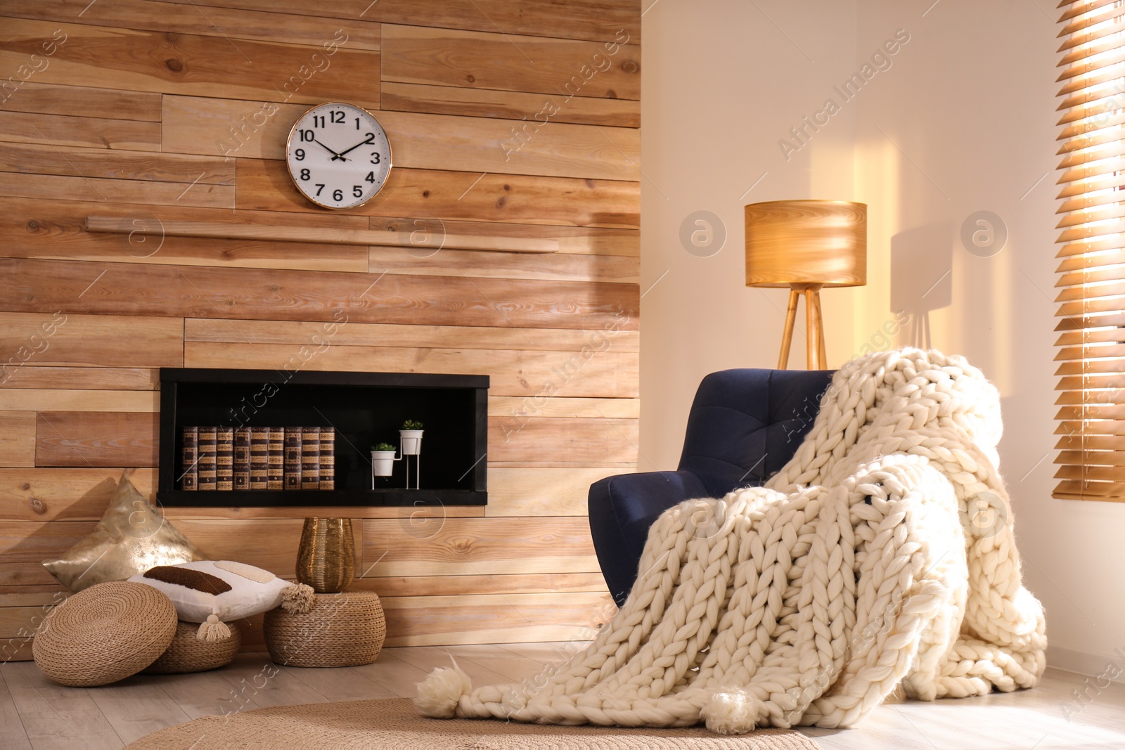 Photo of Soft knitted blanket on armchair in living room. Interior element