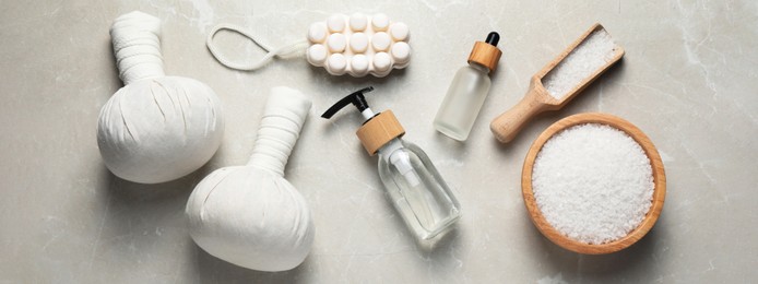 Image of Flat lay composition with herbal massage bags and other spa products on light grey marble table. Banner design