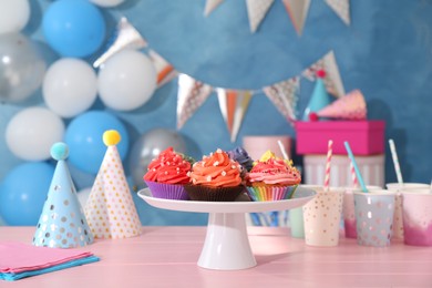 Photo of Different colorful cupcakes and party accessories on pink table