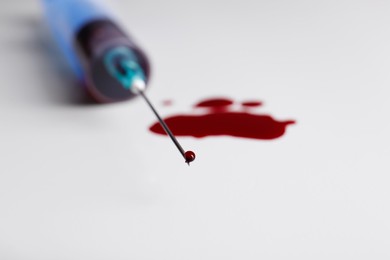 Plastic syringe with blood on white background