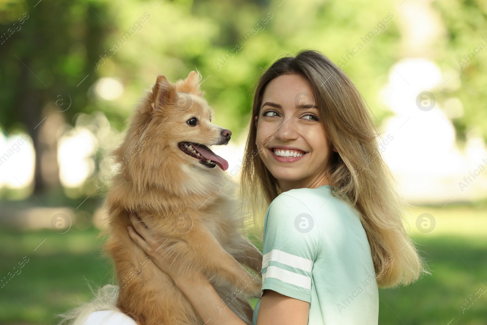 Photo of Young woman with her cute dog in park on sunny day