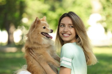 Photo of Young woman with her cute dog in park on sunny day