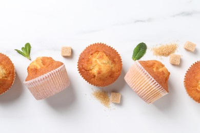 Photo of Delicious sweet muffins and brown sugar on white marble table, flat lay