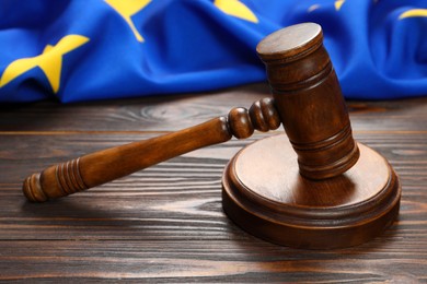 Judge's gavel and flag of European Union on wooden table, closeup