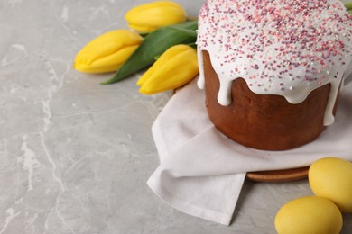 Photo of Tasty Easter cake, decorated eggs and flowers on grey table. Space for text