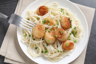 Photo of Delicious scallop pasta with green onion served on grey table, top view