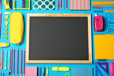 Photo of Flat lay composition with different school stationery and small chalkboard on color background