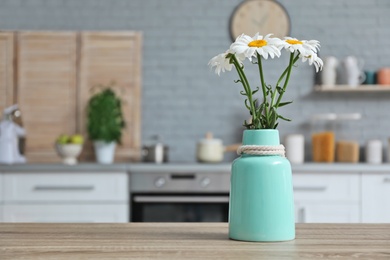 Photo of Vase with flowers and blurred view of kitchen interior on background