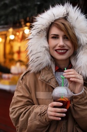 Photo of Woman with cup of mulled wine at winter fair