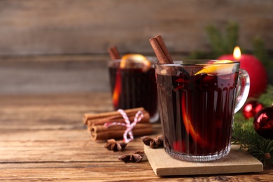 Photo of Aromatic mulled wine on wooden table, space for text