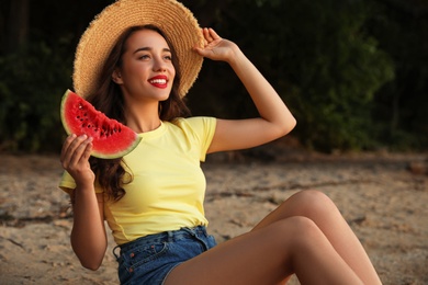 Beautiful young woman with watermelon on sandy beach