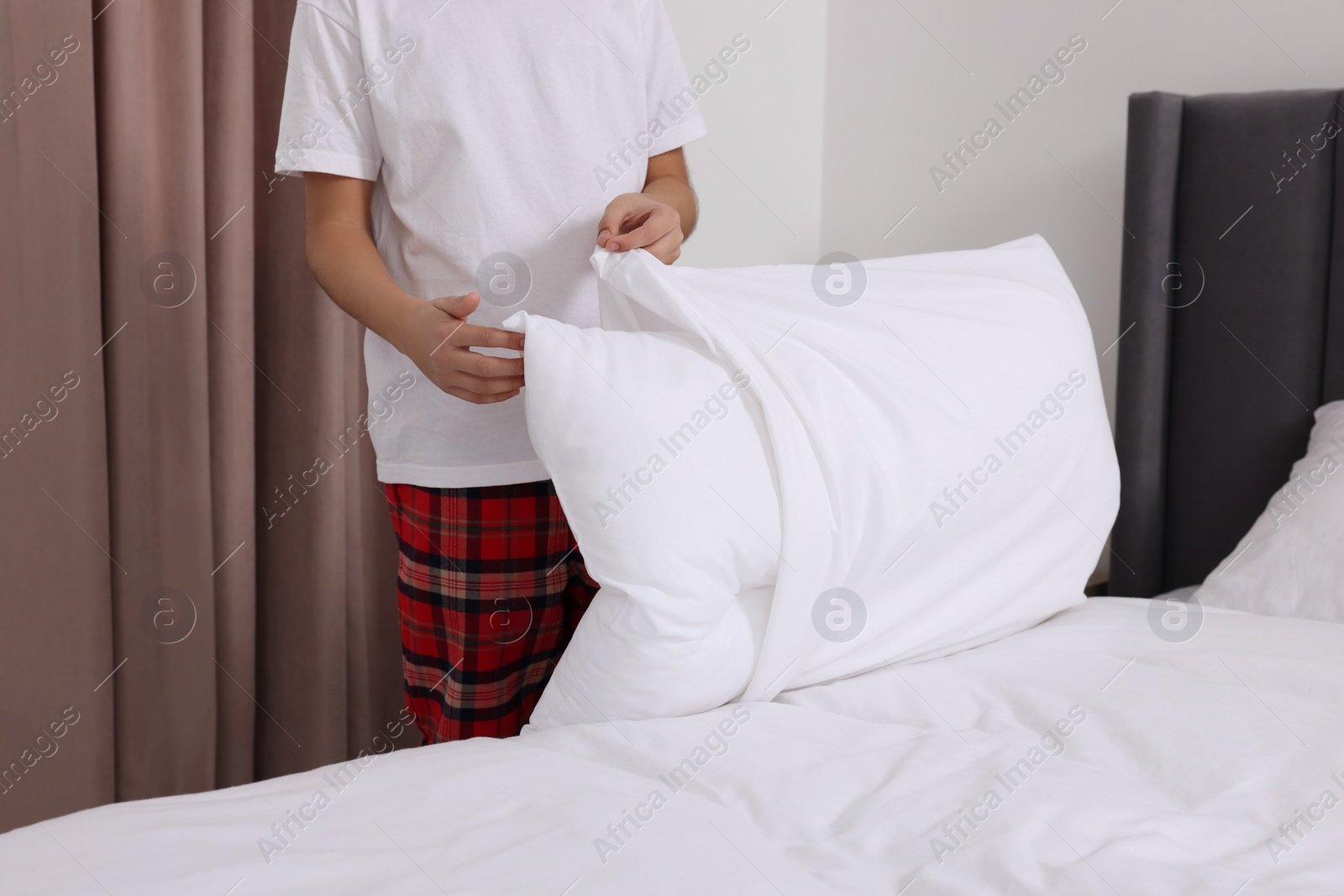 Photo of Boy changing pillowcase in bedroom, closeup. Domestic chores